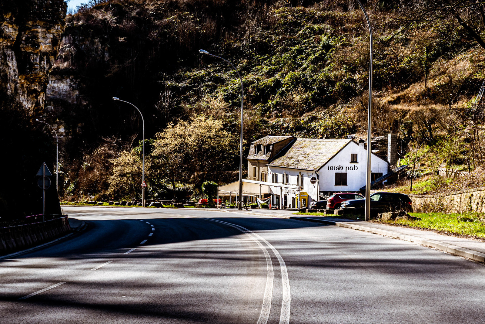 Straße im Alzette-Tal, Pulvermühl, gesäumt von Felsen und Bäumen unter klarem Himmel. - ©LCTO_0010702_ORI