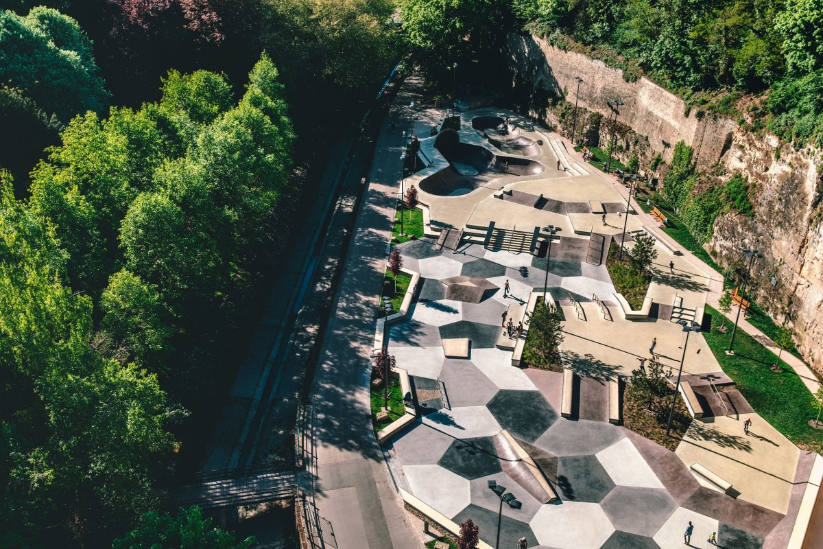 Modern skatepark in Pétrusse Valley, Luxembourg City, surrounded by cliffs and greenery, aerial view.